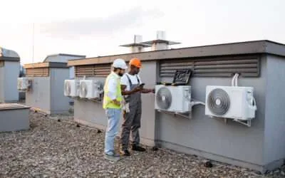 Two construction workers on a roof inspecting cooling equipment